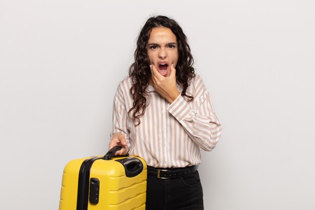 Young hispanic woman with mouth and eyes wide open and hand on chin, feeling unpleasantly shocked, saying what or wow