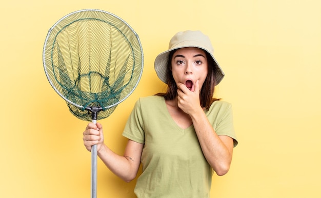 Photo young hispanic woman with mouth and eyes wide open and hand on chin fish net concept