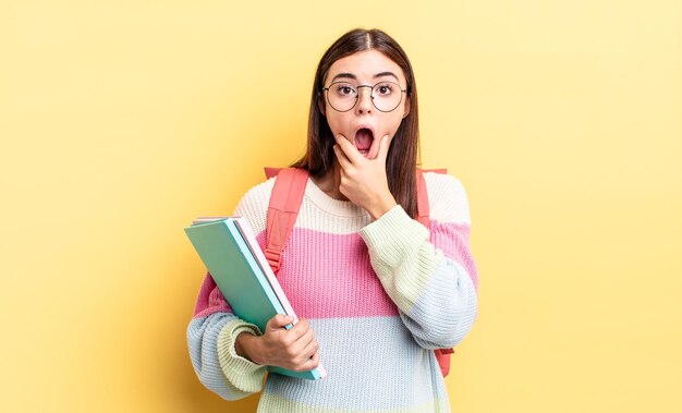 Young hispanic woman with mouth and eyes wide open and hand on chin. student concept