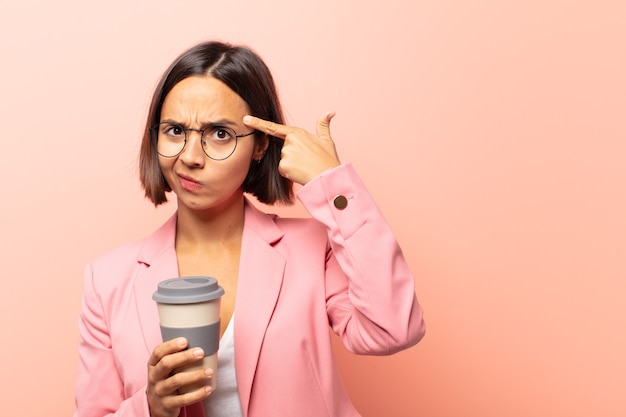 Giovane donna ispanica con uno sguardo serio e concentrato, che fa brainstorming e pensa a un problema impegnativo