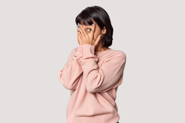 Photo young hispanic woman with short black hair in studio blink through fingers frightened and nervous