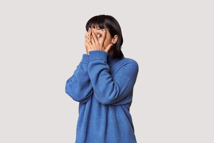 Photo young hispanic woman with short black hair in studio blink through fingers frightened and nervous