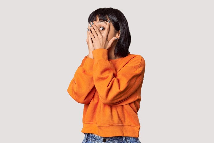 Photo young hispanic woman with short black hair in studio blink through fingers frightened and nervous