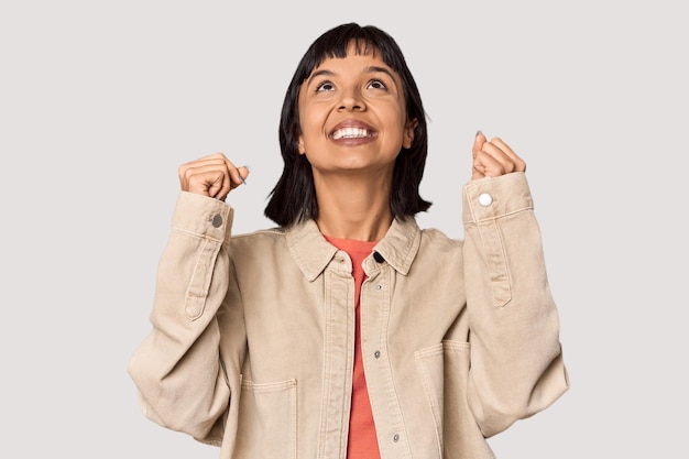 Young Hispanic woman with short black hair in studio celebrating a victory passion