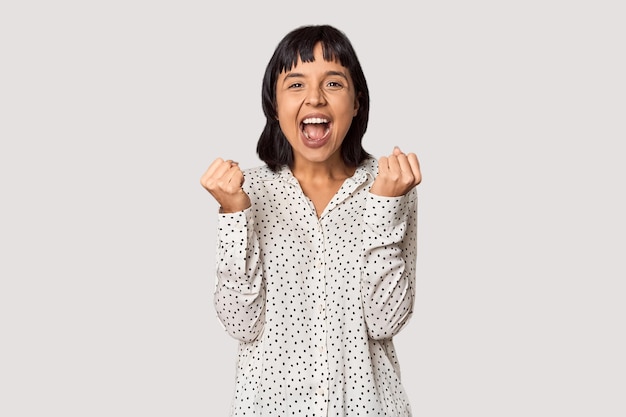 Young Hispanic woman with short black hair in studio cheering carefree and excited Victory concept