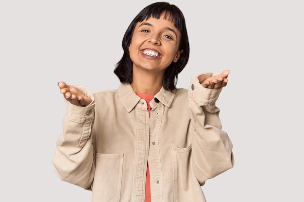 Young Hispanic woman with short black hair in studio feels confident giving a hug to the camera