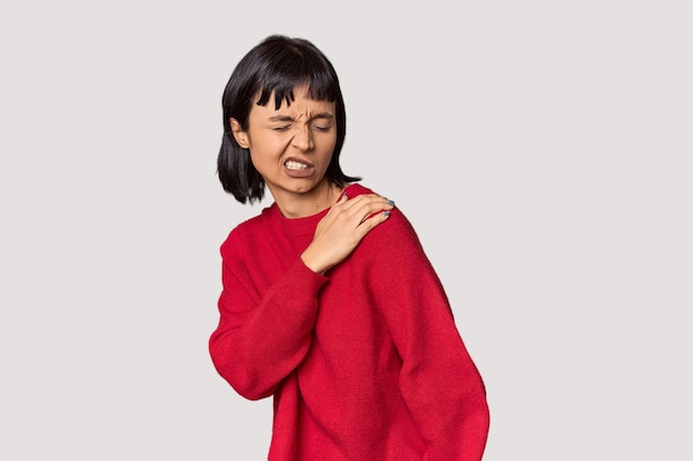 Young Hispanic woman with short black hair in studio having a shoulder pain