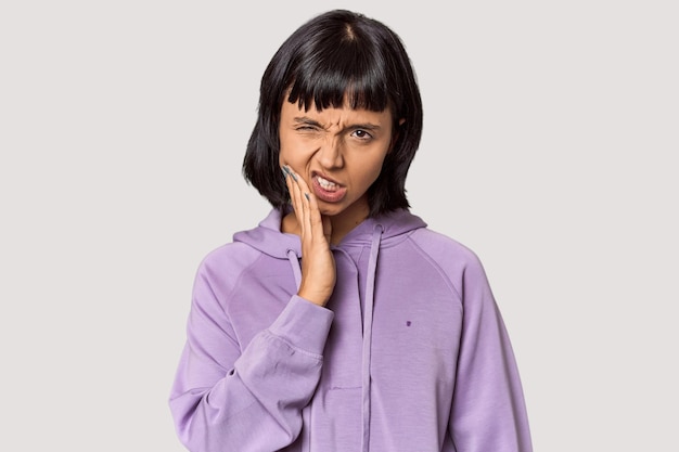 Young Hispanic woman with short black hair in studio having a strong teeth pain molar ache