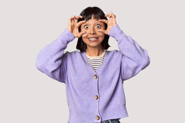 Young Hispanic woman with short black hair in studio keeping eyes opened to find a success