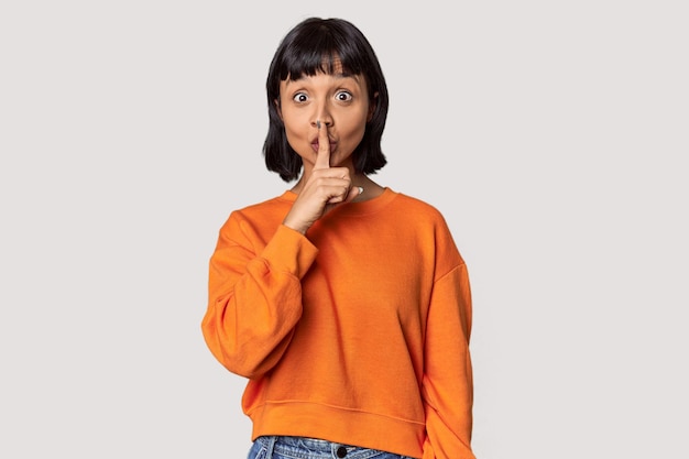 Photo young hispanic woman with short black hair in studio keeping a secret or asking for silence