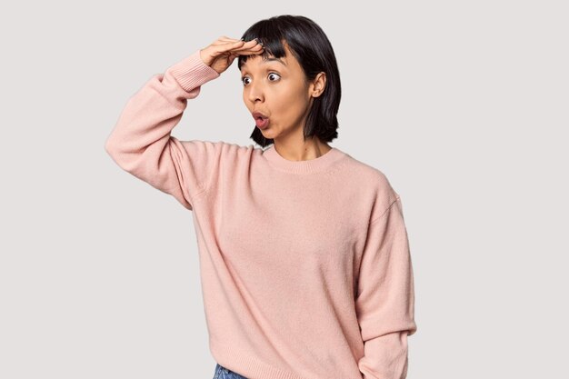 Photo young hispanic woman with short black hair in studio looking far away keeping hand on forehead