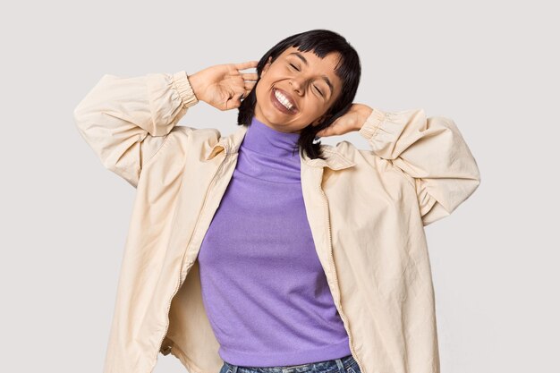 Young Hispanic woman with short black hair in studio stretching arms relaxed position