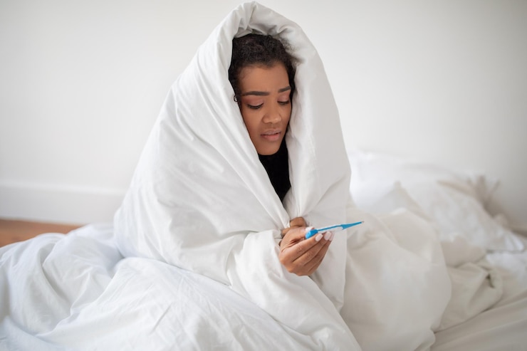 Photo a young hispanic woman wrapped cozily in a white blanket is sitting on her bed while intently