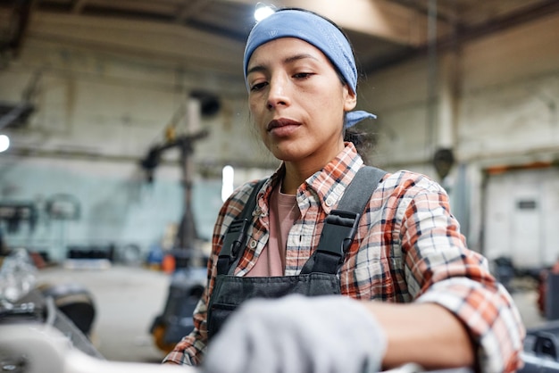 Photo young hispanic workwoman or repairperson in coveralls blue headband and gloves