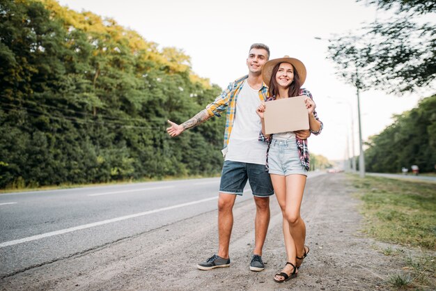 Young hitchhiking couple with empty cardboard