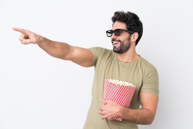 Young holding a big bowl of popcorns over isolated wall 