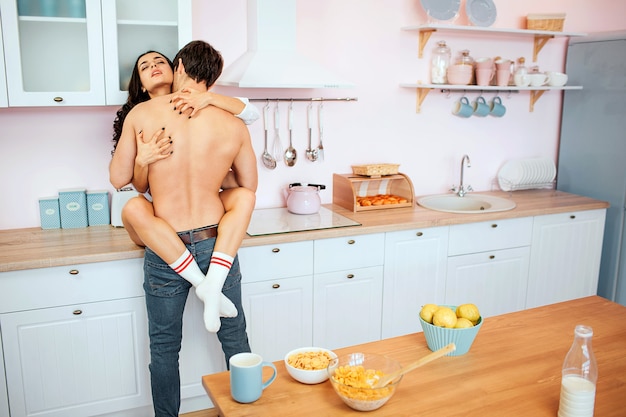 Young hot couple having sex on kitchen cabinet. She sit there and embrace guy with legs.