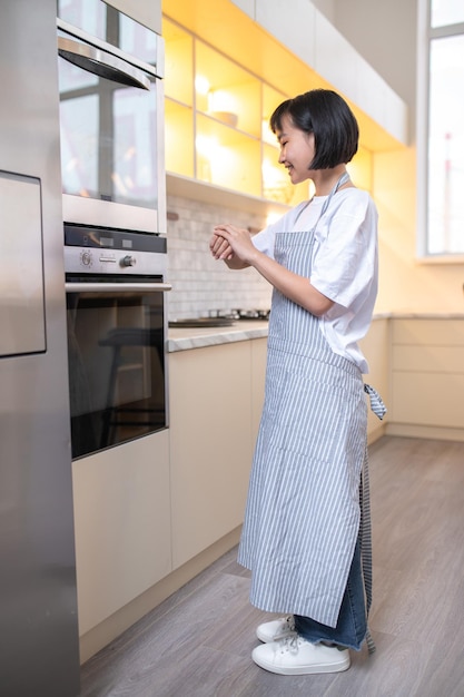 Молодая домохозяйка готовит на кухне и выглядит заинтересованной и взволнованной