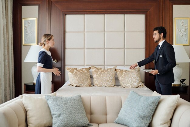 Young housekeeping manager of five star hotel instructing chambermaid