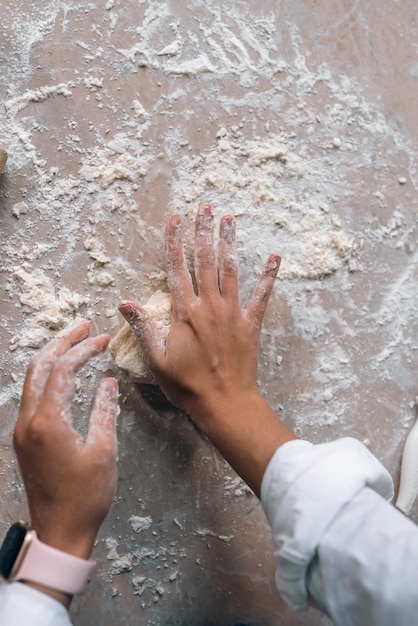 Young housewife in an apron kneads dough with her hands