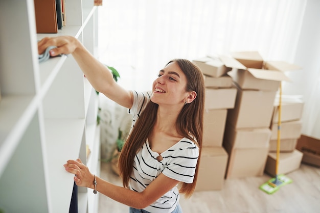 若い主婦が新しいアパートを掃除します。アイテムが入った箱を開梱する準備をしています。