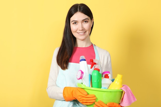 A young housewife holds in his hands cleaning products on a colored background