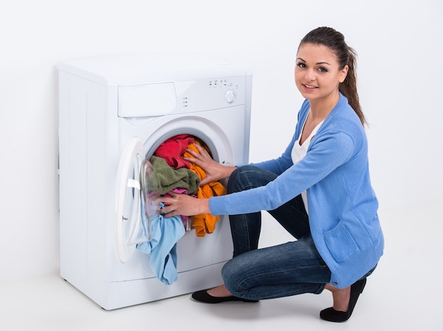 Young housewife is doing laundry with washing machine.