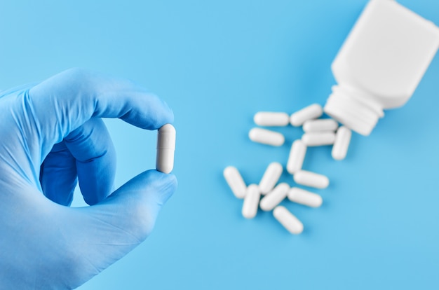 Молодые человеческие руки держат таблетки таблетки в ладони. Здравоохранение, медицинская и фармацевтическая концепция. Изолированные на синем фоне.