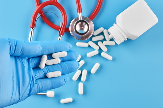 Young human hand hold pills tablets in palm. Healthcare, medical and pharmaceutical concept. Isolated on blue background.