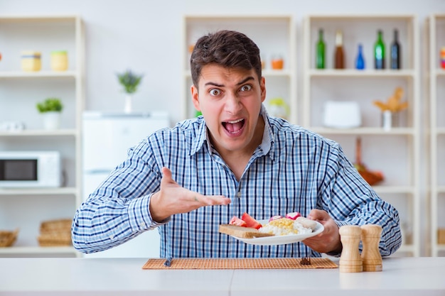 Young husband eating tasteless food at home for lunch