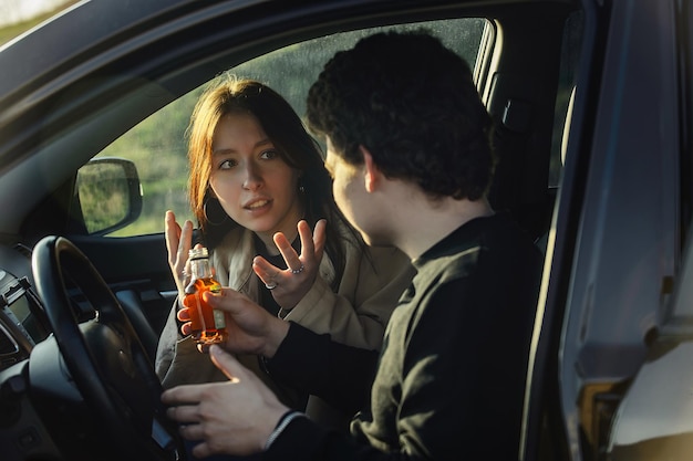 молодые муж и жена ссорятся в машине из-за алкоголя