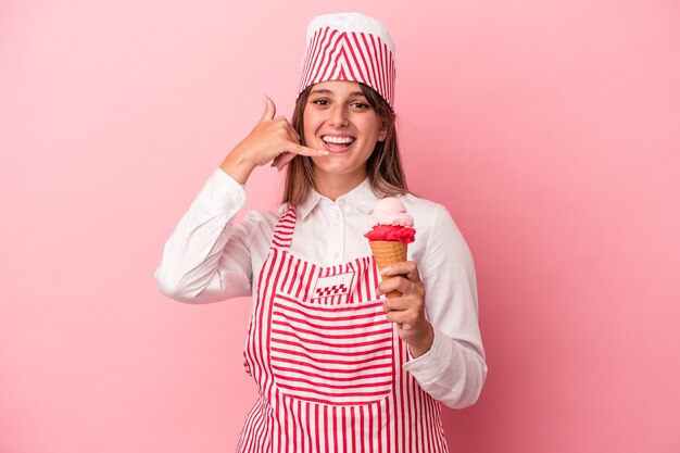 young ice cream maker woman holding ice cream isolated on pink background showing a mobile phone call gesture with fingers.