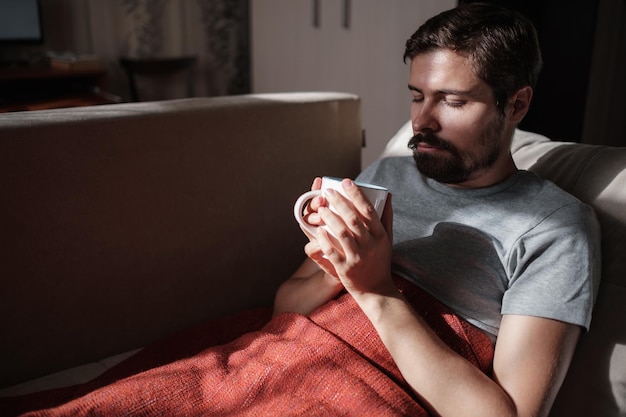 Young ill man drinking hot tea at home