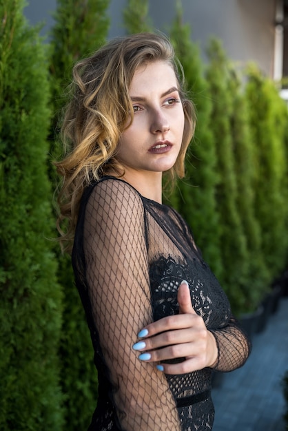 Young incredibly pretty woman posing at camera in between white cedar. Relaxation and outdoor recreation