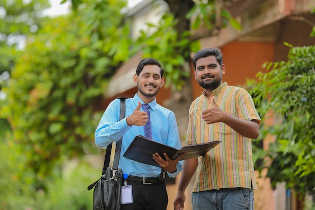 Young india bank officer completing paper work with farmer.