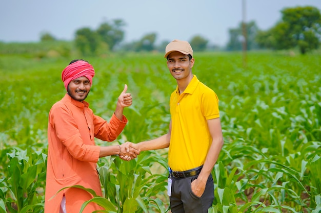 Young indian agronomist or banker shake hand with farmer at agriculture field.