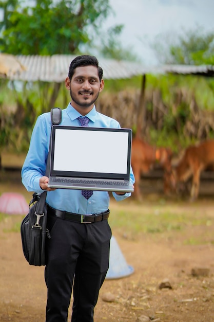 Young indian agronomist or banker showing laptop screen