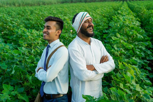 Foto giovane agronomo indiano o banchiere che mostra alcune informazioni all'agricoltore nel campo agricolo