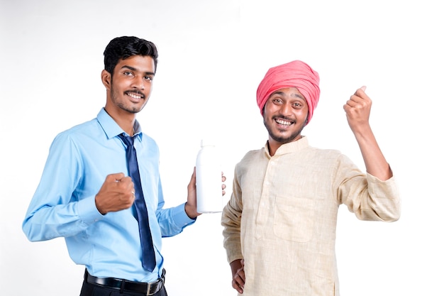 Young indian agronomist giving bottle to farmer on white background.