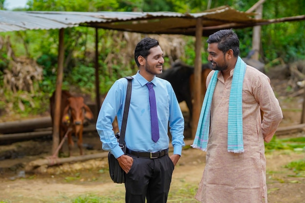 Young indian agronomist or officer visiting to farmer at his farm