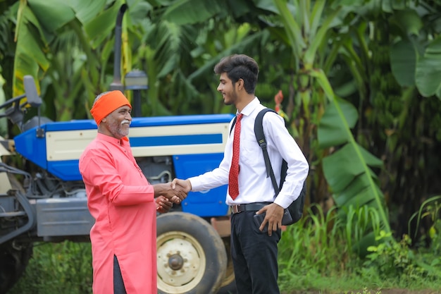 Young indian agronomist shack hand with farmer in field