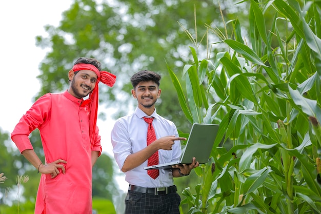 옥수수 밭에서 농부에게 몇 가지 정보를 보여주는 젊은 인도 경제학자