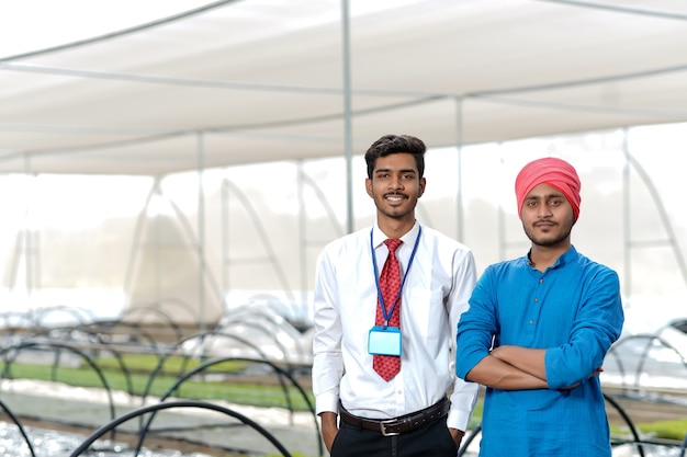 Young indian agronomist with farmer at greenhouse