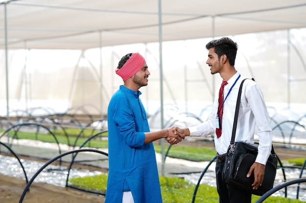 Young indian agronomist with farmer at greenhouse