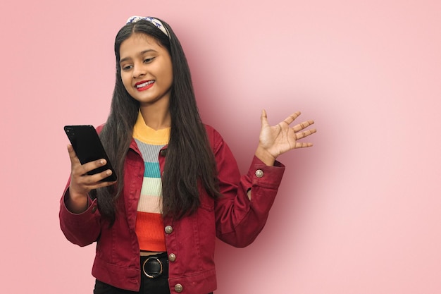 어린 인도 아시아 10대 소녀가 고립된 미소를 짓고 모의 복사 공간이 있는 휴대전화로 메시지를 주고받고 있다
