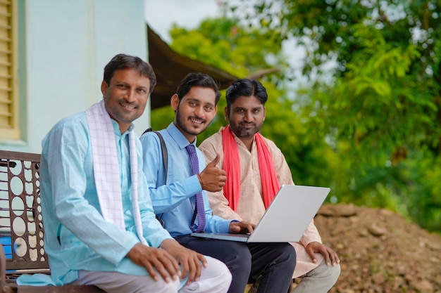 젊은 인도 은행가나 농업경제학자는 집에서 노트북으로 농부들에게 몇 가지 세부 사항을 보여줍니다.