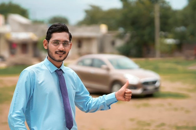 車で立っている若いインドの銀行家または金融業者