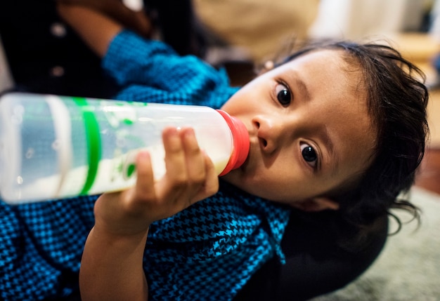 Photo young indian boy drinking milk from bottle
