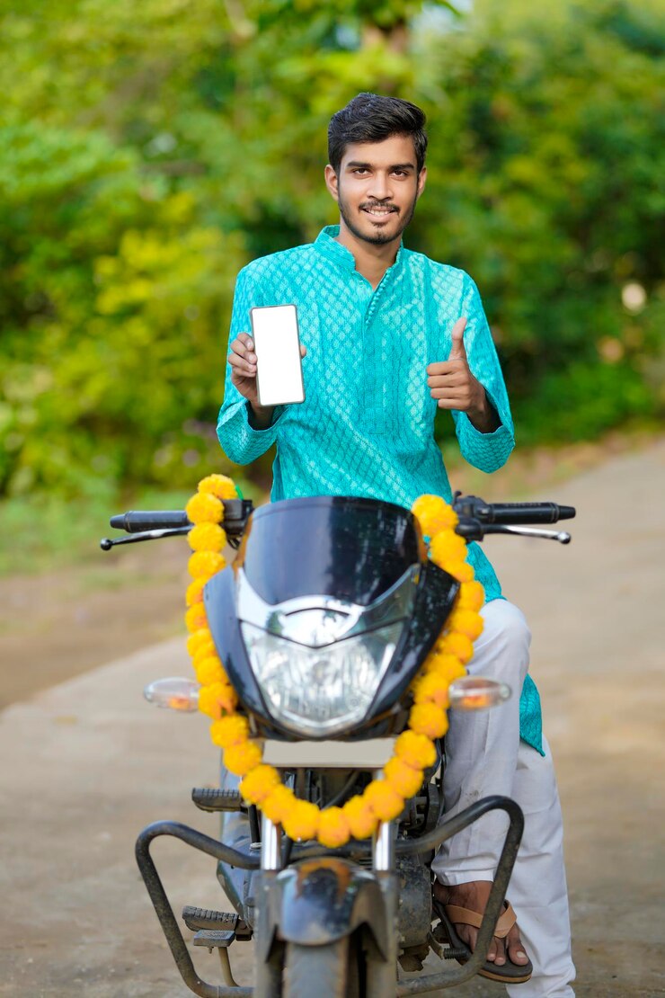 फोटो young indian boy in ethnic wear and showing smartphone with new bike