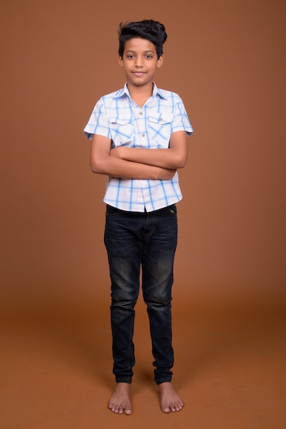 Young Indian boy wearing checkered shirt against brown background